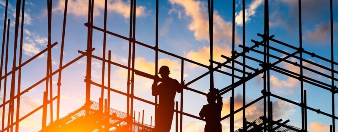 Silhouettes of workers on scaffolding at a construction site during sunset under the heading ‘Patents Update’.